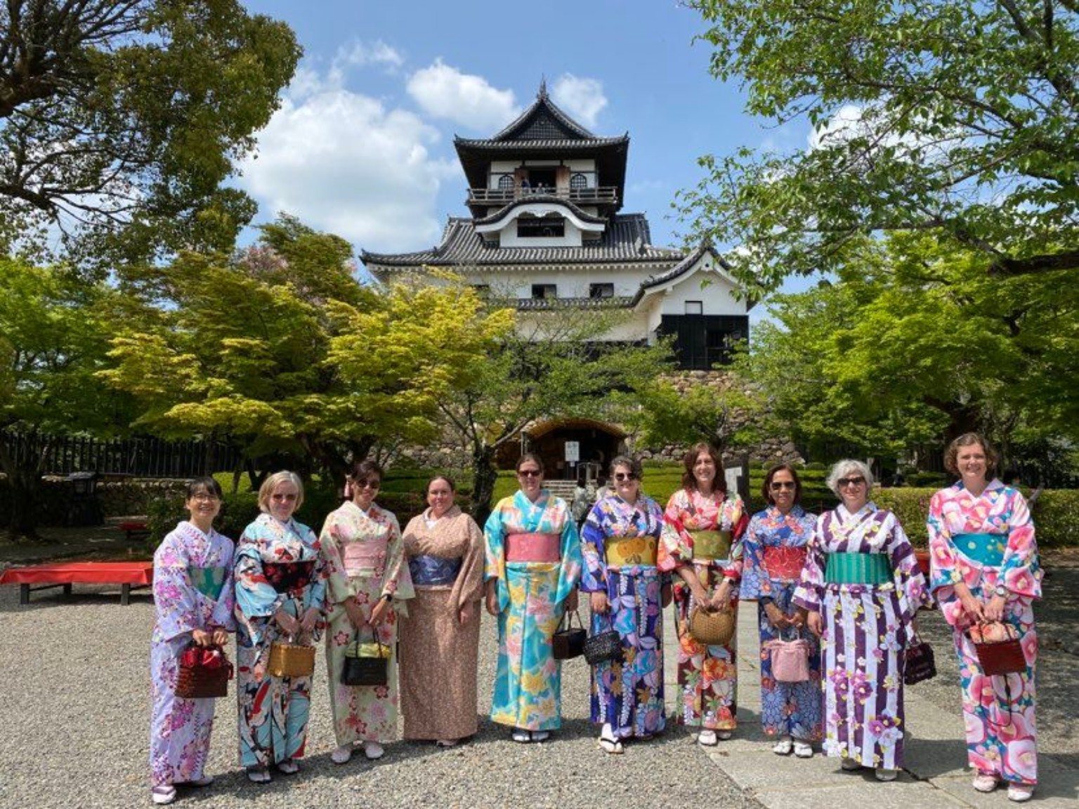 A small group wearing colorful kimono in front of Inuyama Castle