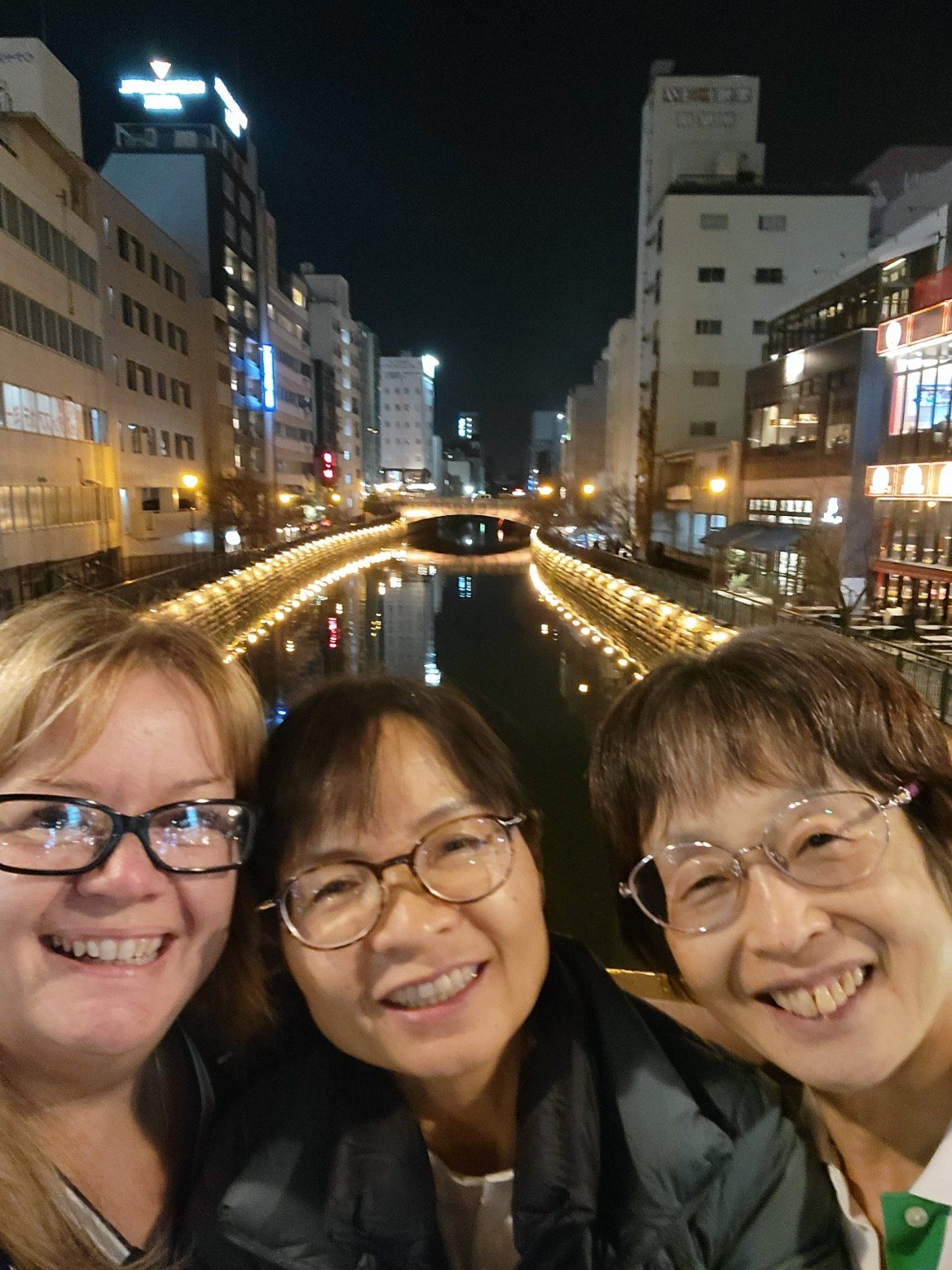 Friends together beside a lit Nagoya canal at night